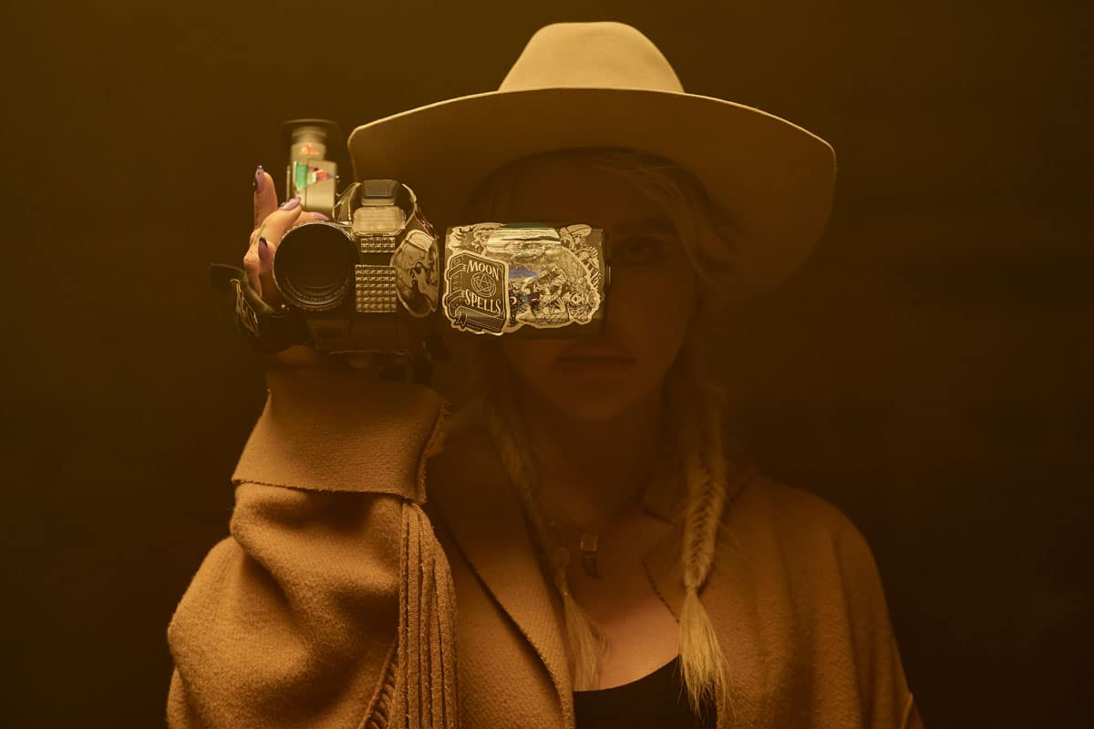 Kesha holding a black video camera.
